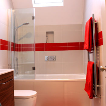 White bathroom suite with a strip of red tiles and accessories to add interest.